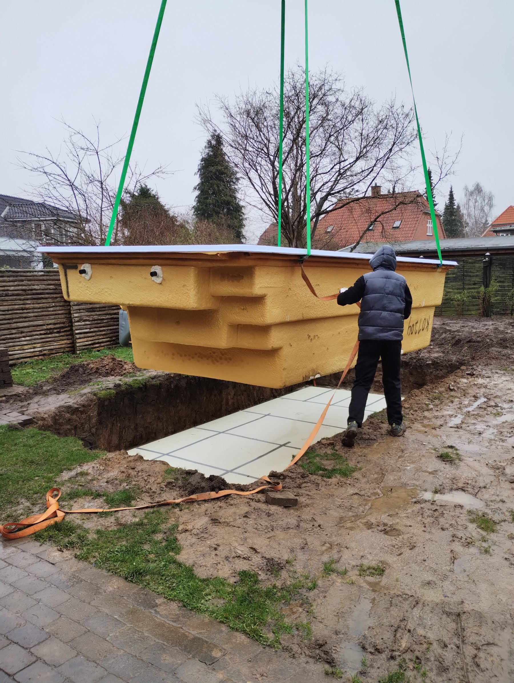 The pool is lifted into place by crane over the excavated hole